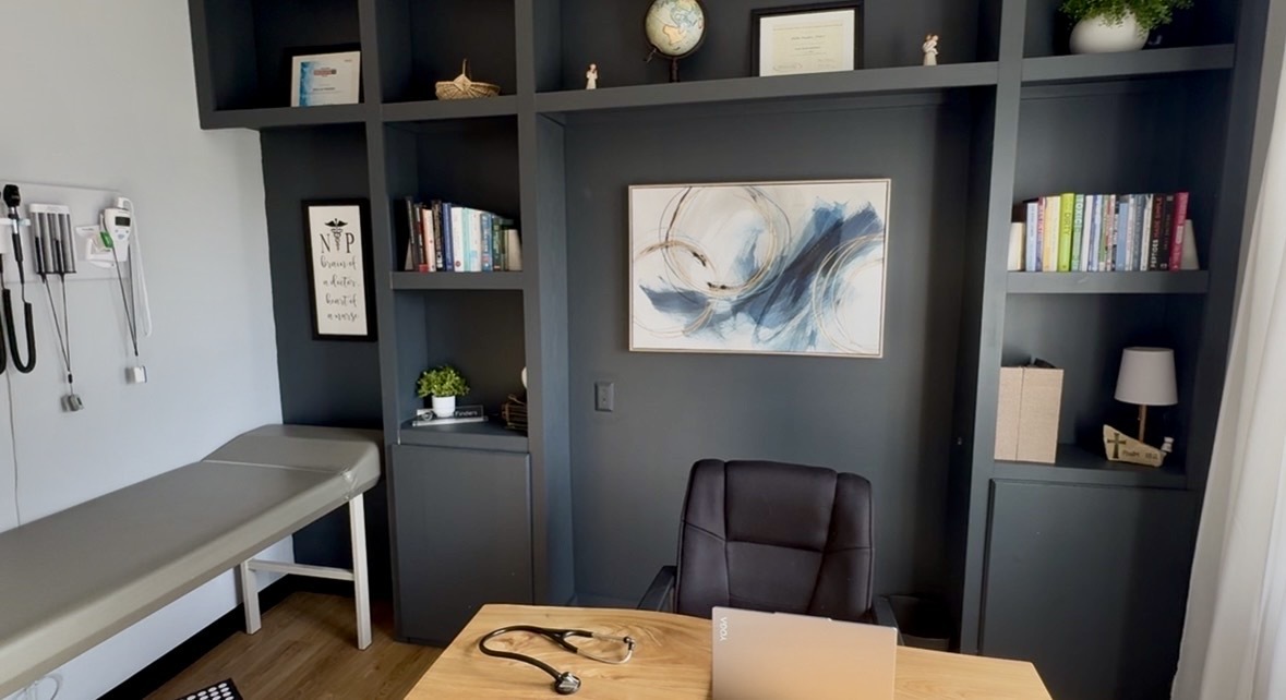 Photo of consultation room with blue built in bookshelf and wooden desk