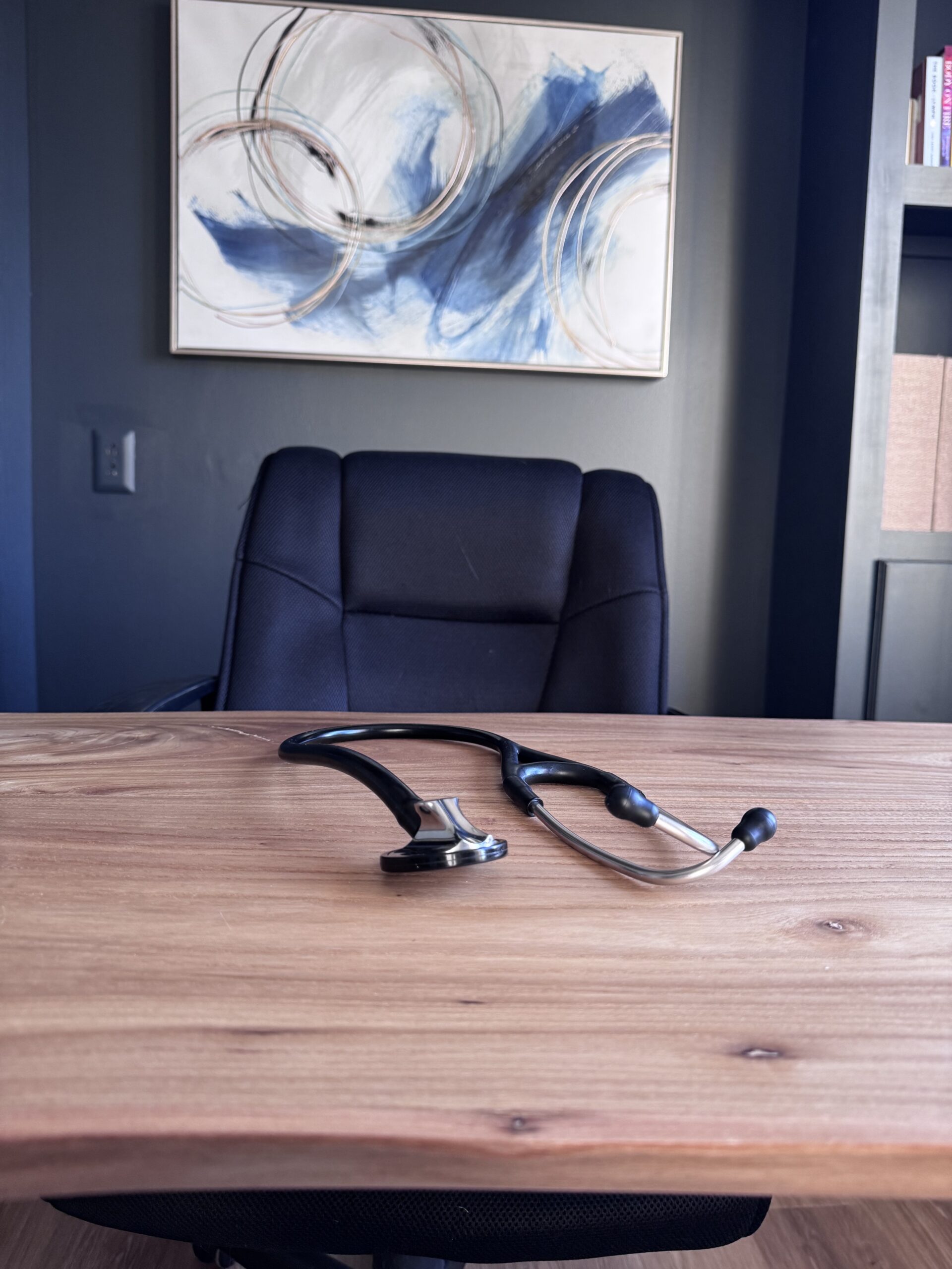 photo of stethoscope on wooden desk in front of chair