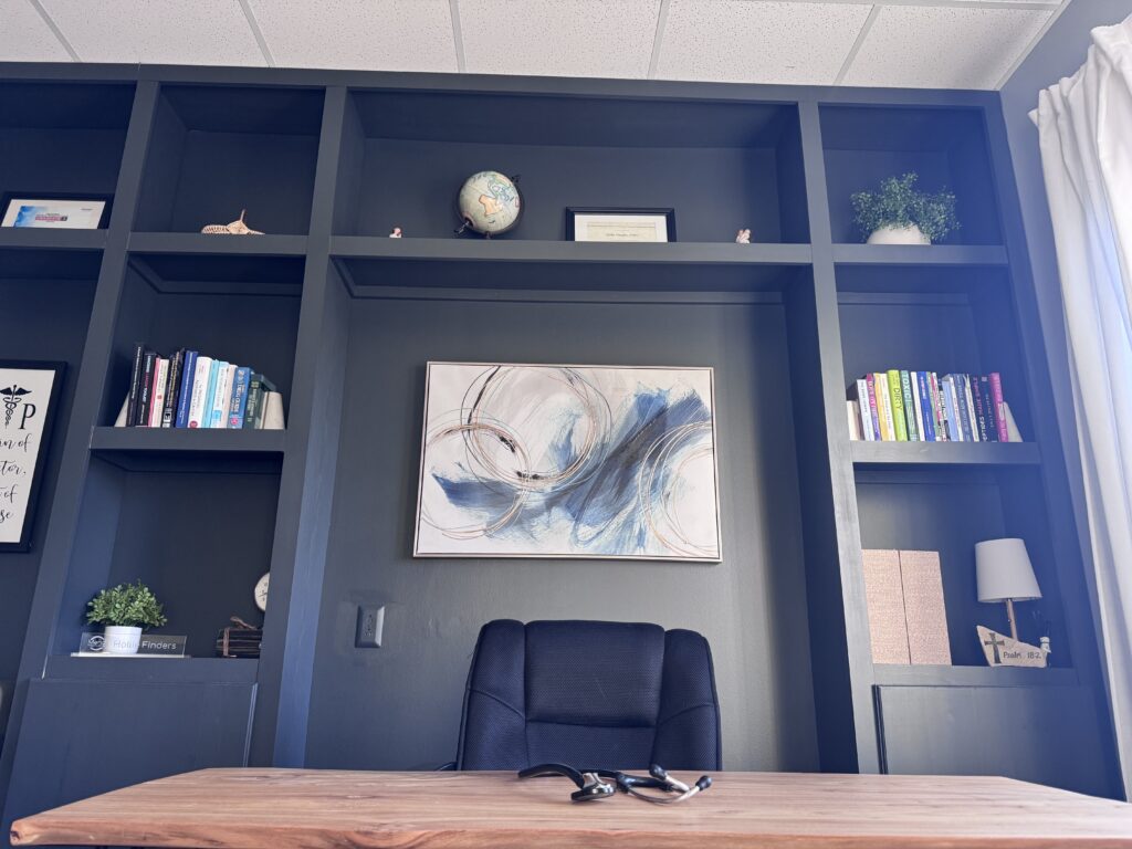 Photo of consultation room with blue built in bookshelf and wooden desk